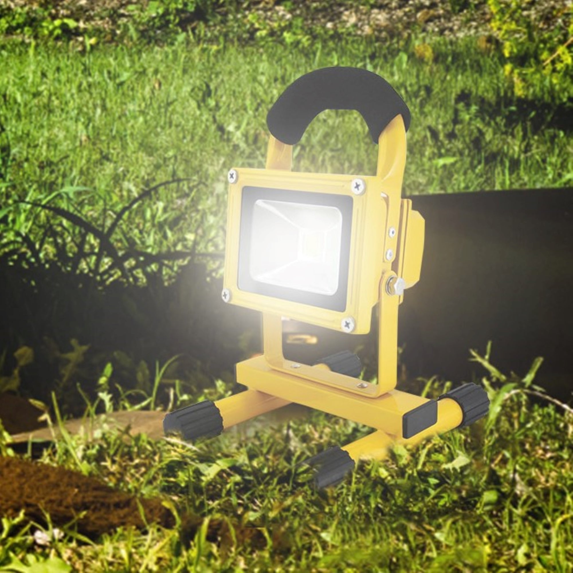 Lifestyle image of 12V rechargeable cordless flood light set up on the grass at night and shining brightly
