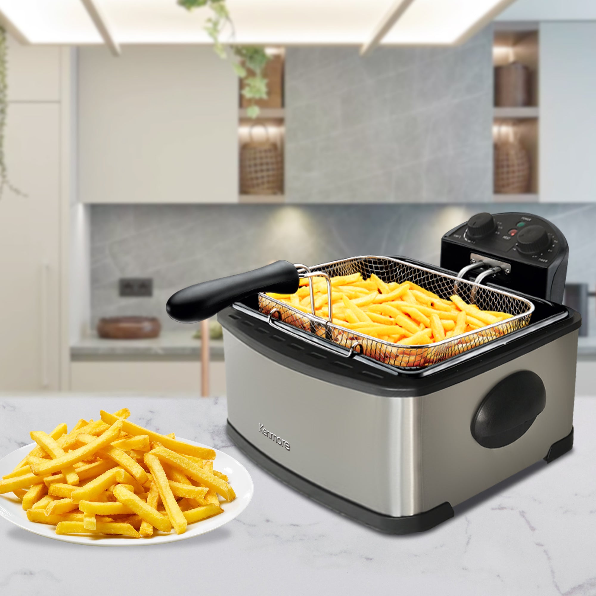 Kenmore deep fryer with and large basket filled with fries and a plate of fries beside it on white and gray marbled kitchen counter