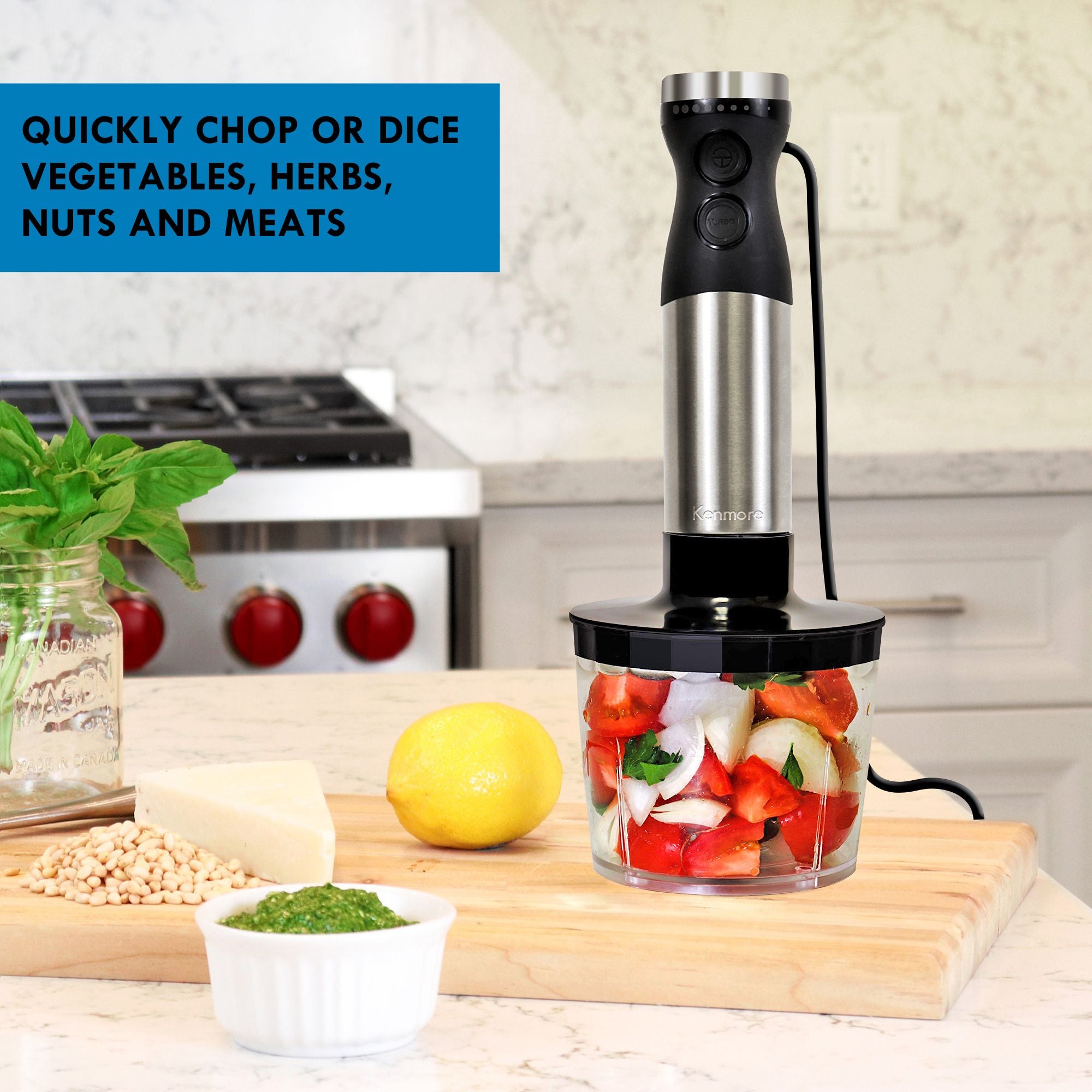 Immersion blender with food chopper attachment filled with cut up peppers, tomatoes, onions, and cilantro on a wooden cutting board with basil, pinenuts, cheese, a lemon, and a small dish of pesto beside it. Text overlay reads, "Quickly chop or dice vegetables, herbs, nuts and meats"