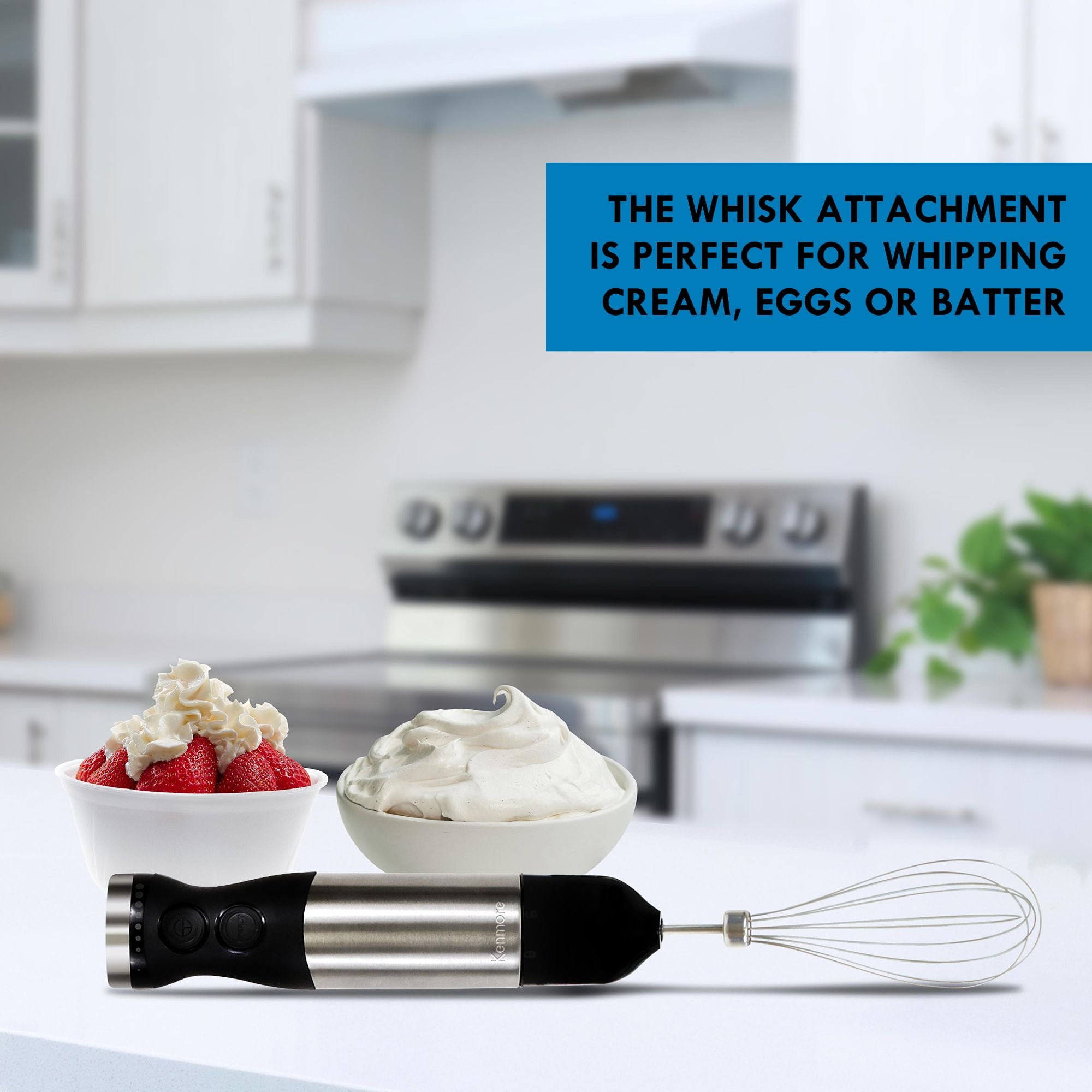 Black and silver hand blender with whisk attachment lying on a white kitchen counter in front of two bowls filled with strawberries and whipped cream. Text overlay reads, "The whisk attachment is perfect for whipping cream, eggs or batter"