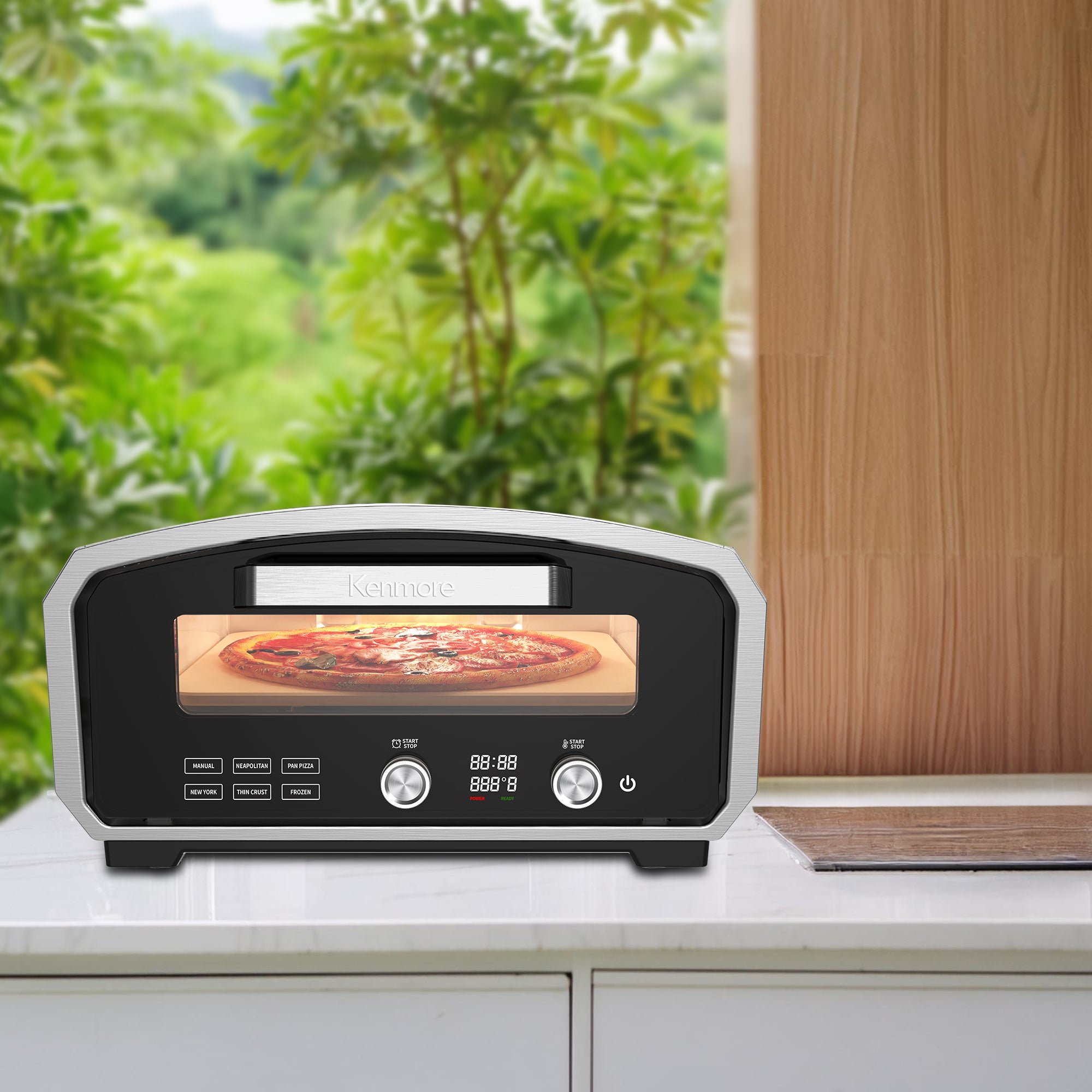 Kenmore countertop outdoor electric pizza oven on a light gray countertop in front of a view of the outdoors