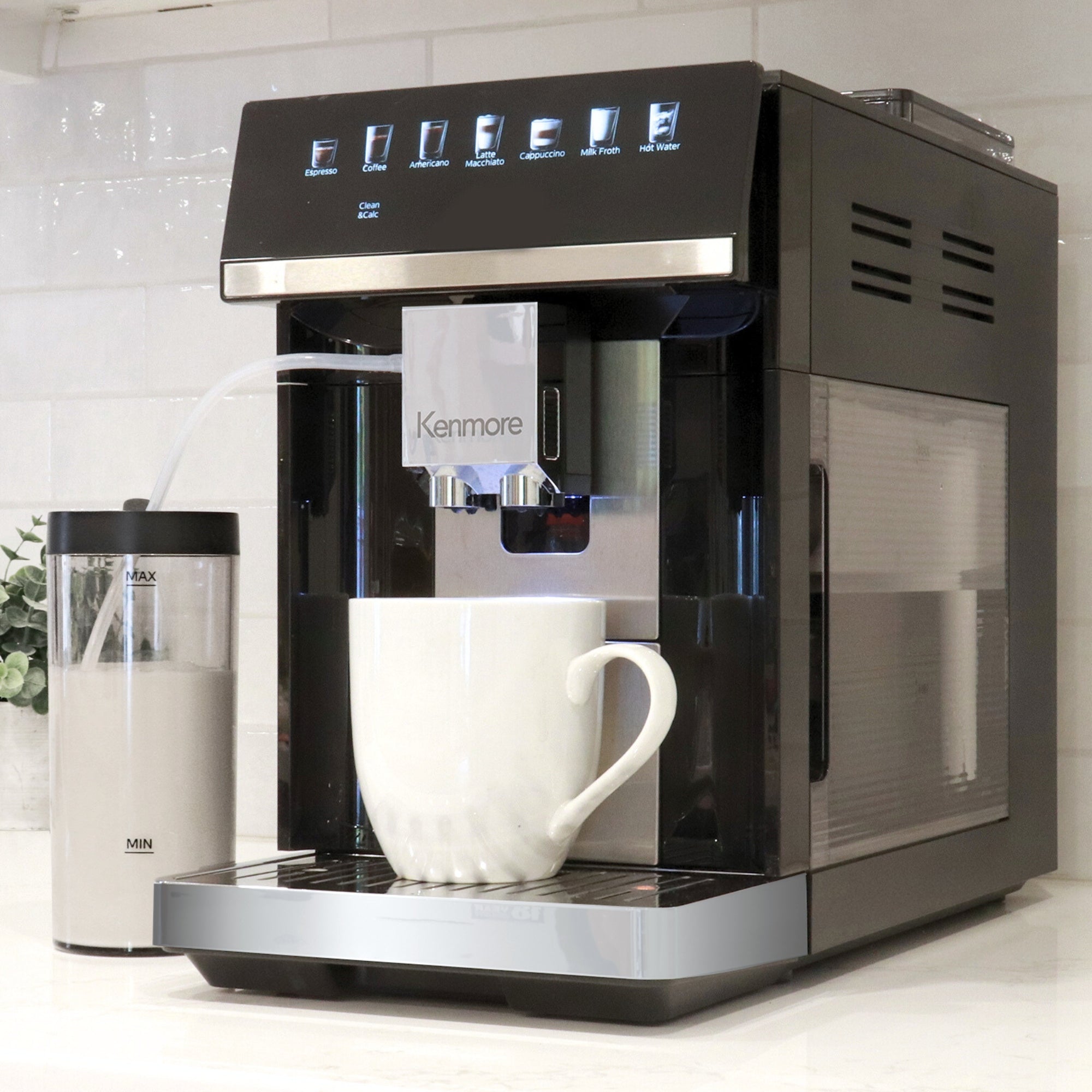 Kenmore fully automatic espresso coffee machine on a white kitchen counter with a white coffee mug below the spout