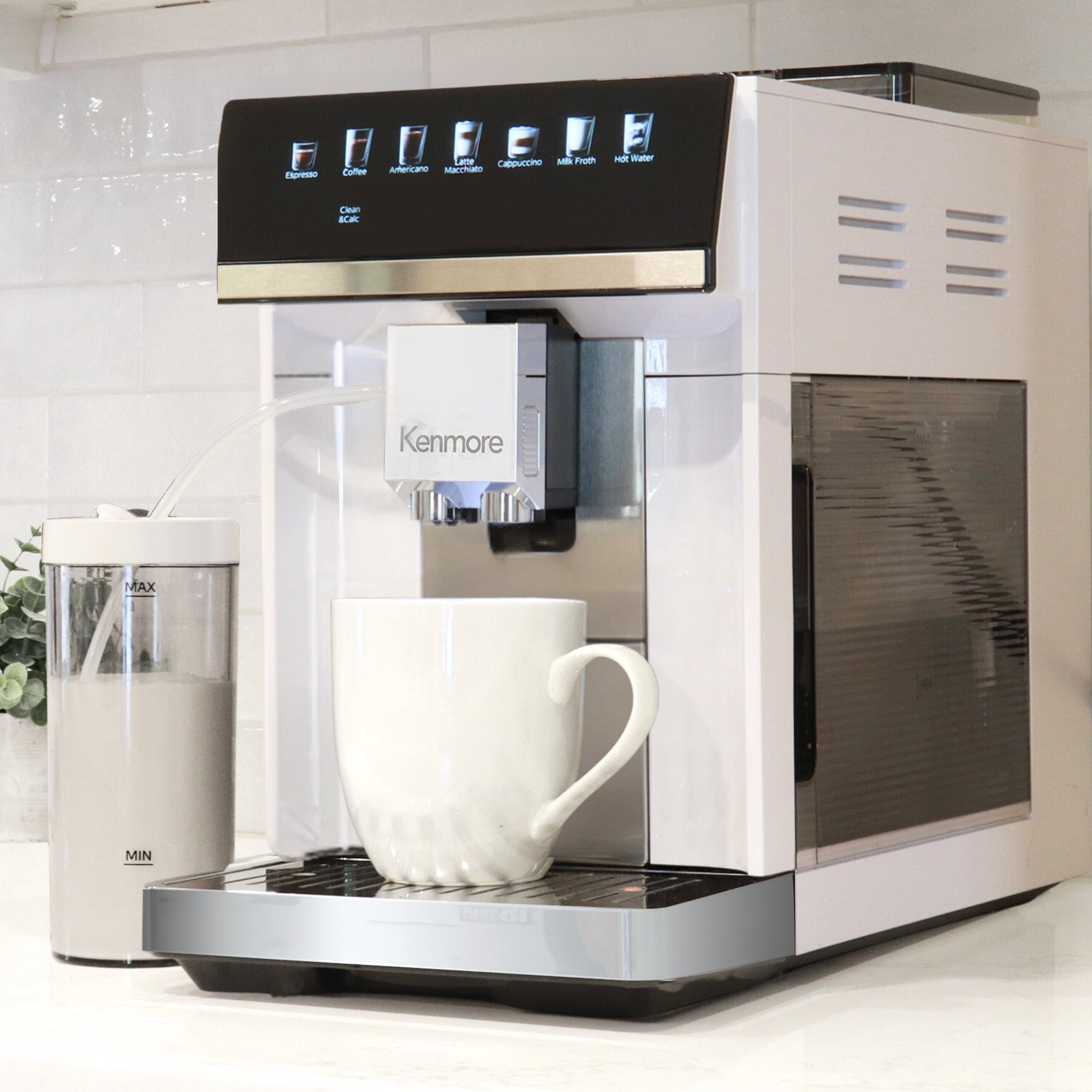 Kenmore fully automatic espresso coffee machine on a white kitchen counter with a white coffee mug below the spout