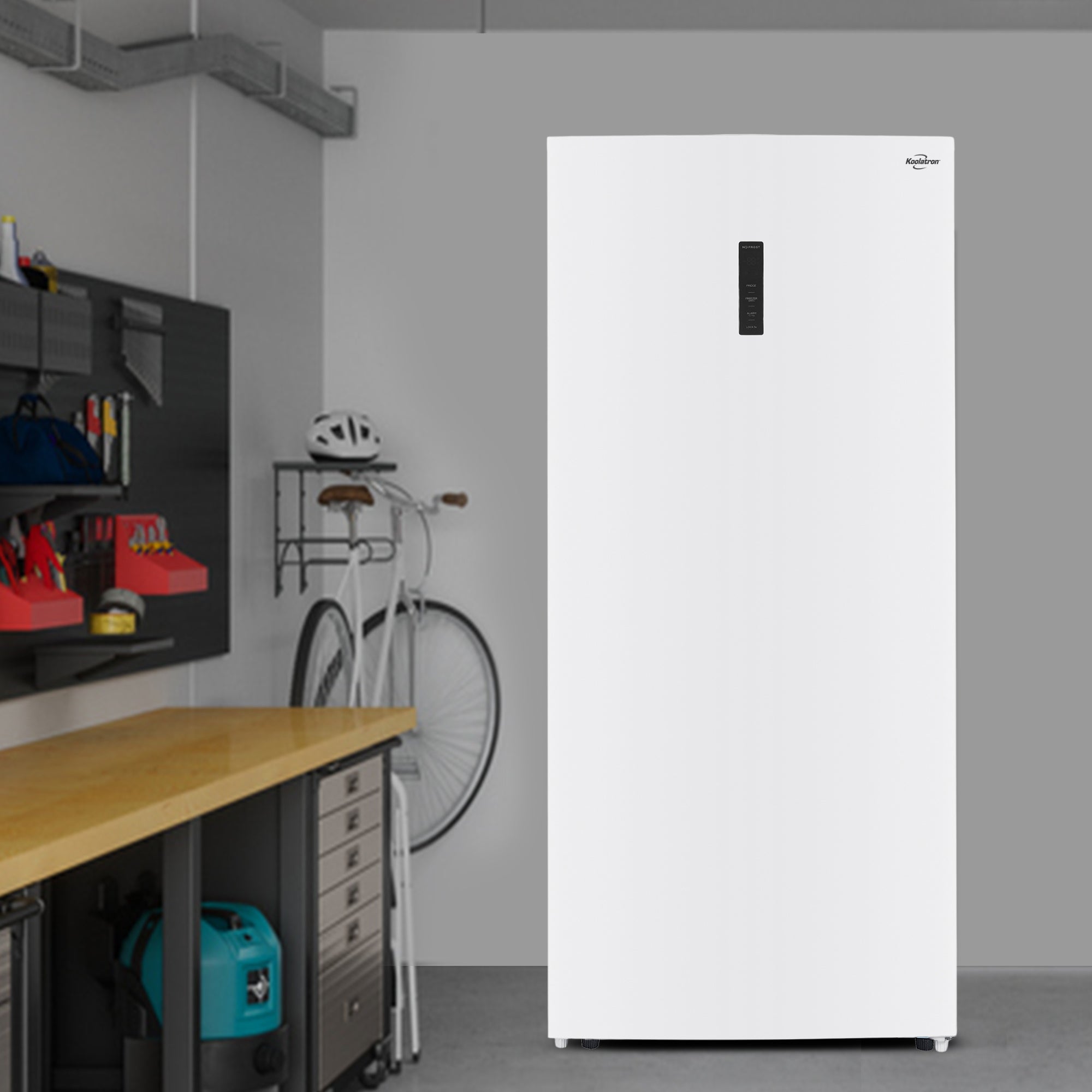 Koolatron convertible upright freezer/refrigerator, closed, in a garage with a tool bench and bicycle beside it