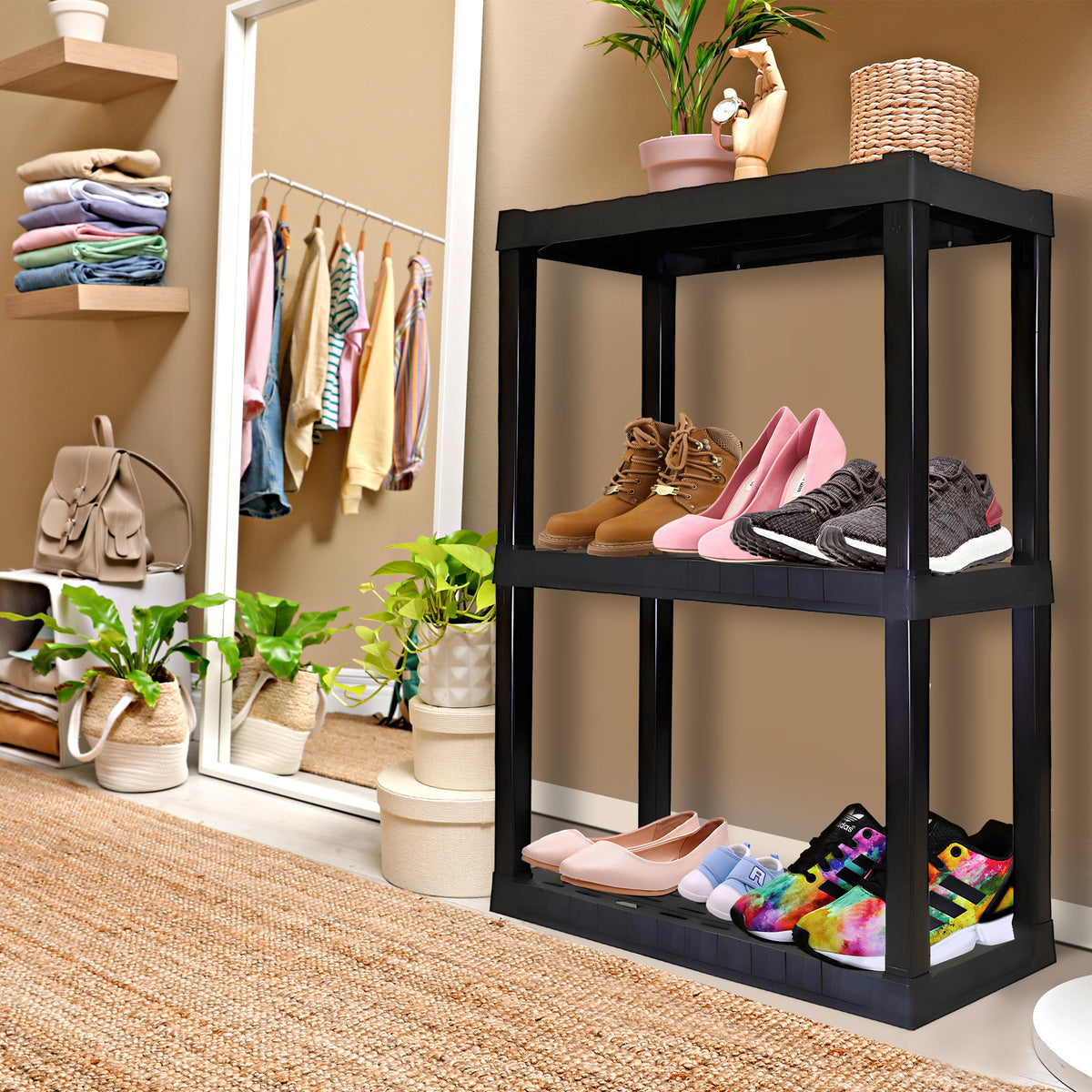 Oskar 3-tier shelf unit being used as a shoe rack with shoes and boots on the shelves beside a mirror reflecting clothes in a closet