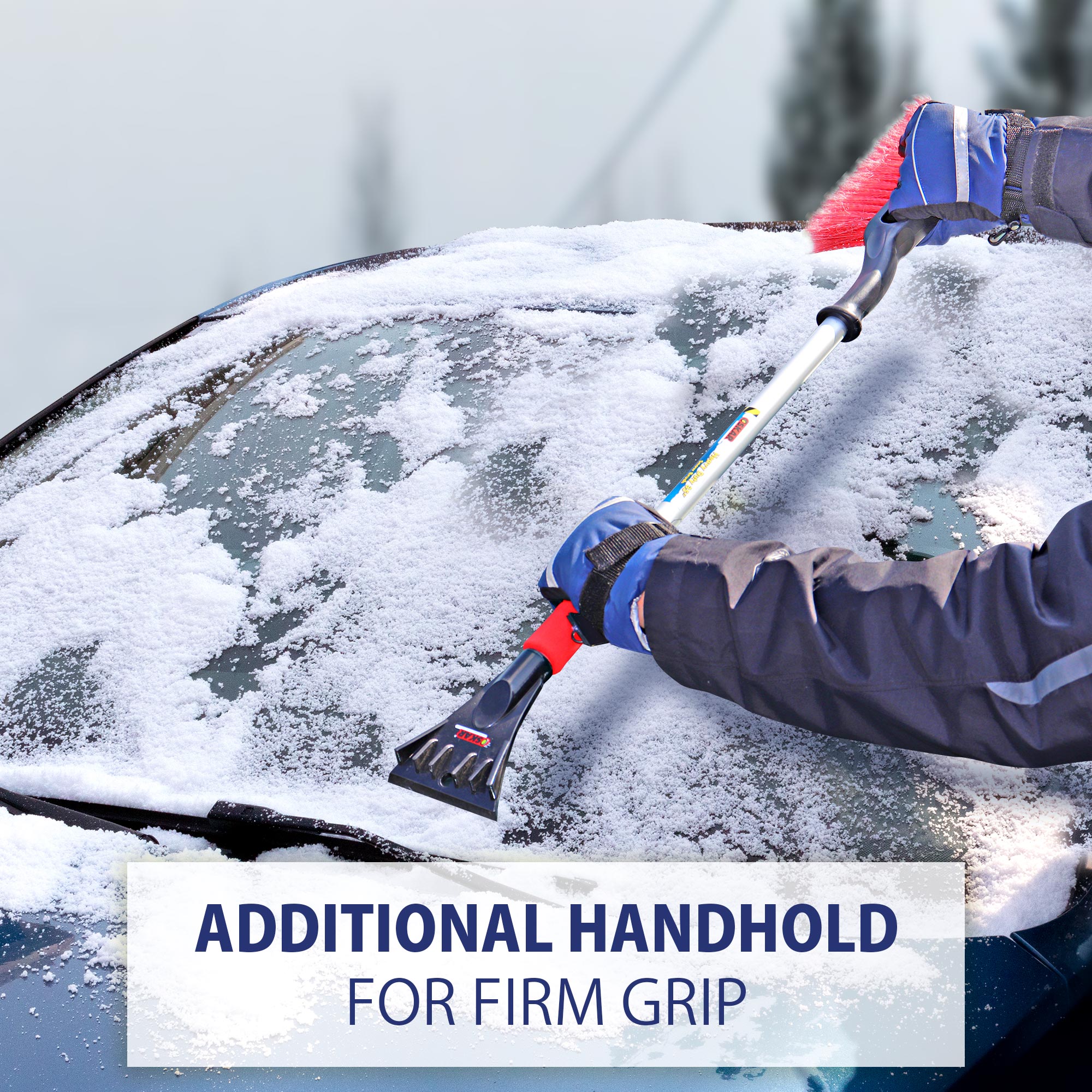 Lifestyle image of a person in winter clothing holding the snow brush with both hands and using the ice scraper to scrape the windshield of a dark coloured car. Transparent white overlay at the top contains text "Additional handhold for firm grip"